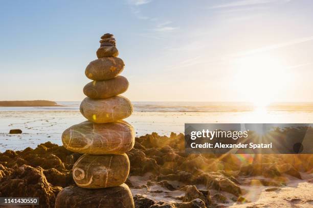 stone cairn pyramid on the beach during sunset - beach stone stock-fotos und bilder