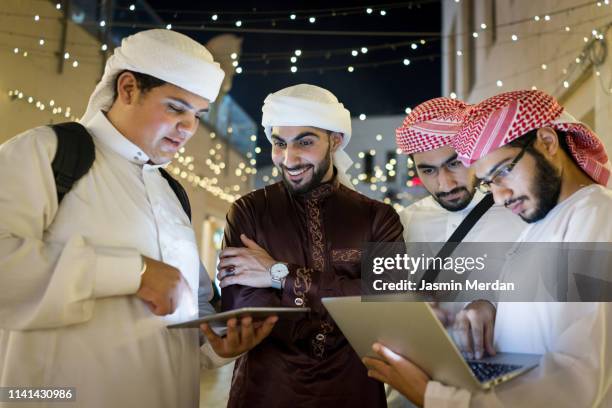 arab young men with laptop on night street - united arab emirates university stock pictures, royalty-free photos & images