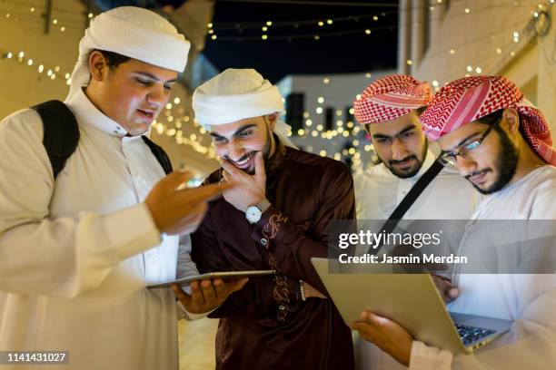 arab young men with laptop on night street - united arab emirates university stock pictures, royalty-free photos & images