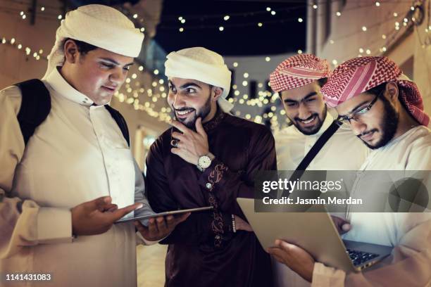 arab young men with laptop on night street - saudi arabia city stock pictures, royalty-free photos & images