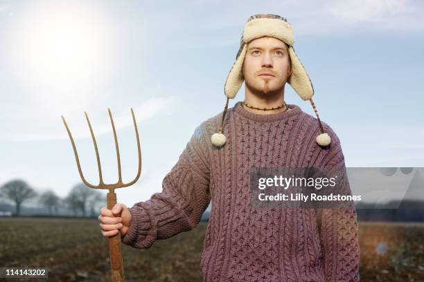 young farmer standing in field - heugabel stock-fotos und bilder