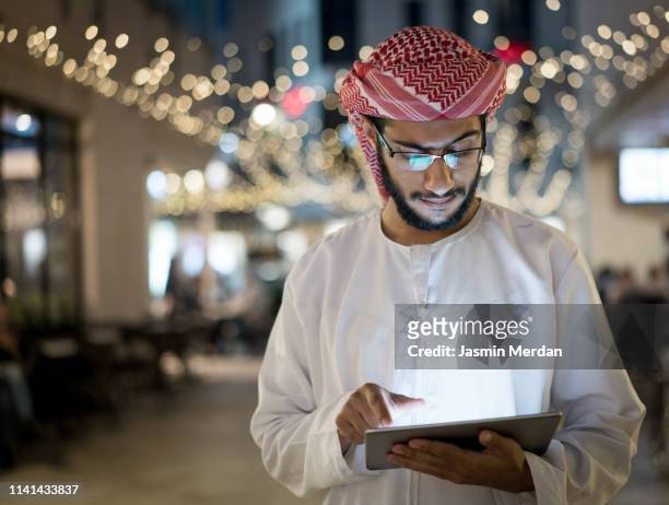 arab young man with tablet outdoors - qatar business stock pictures, royalty-free photos & images