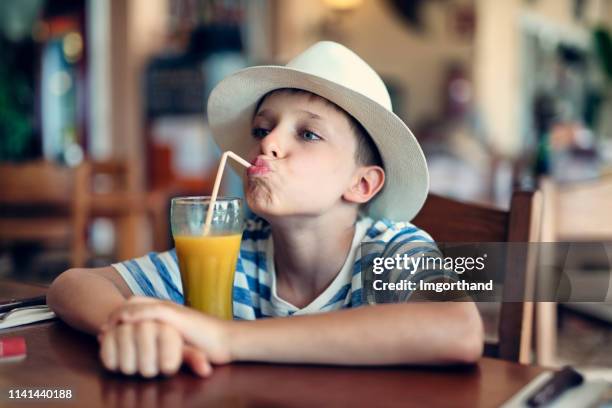 portrait of cute little boy drinking juice at restaurant - orange juice stock pictures, royalty-free photos & images