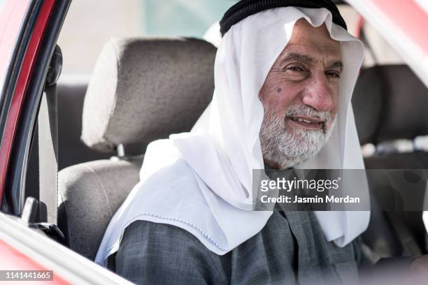 elder arab man in car - arab driving stock-fotos und bilder