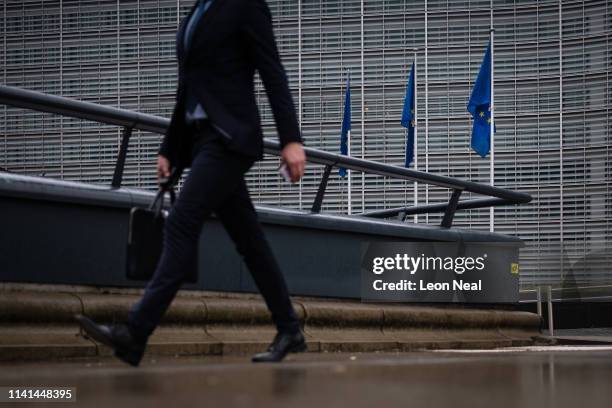 Flags hang on their poles as people avoid the rain near to the headquarters of the European Council of Ministers on April 09, 2019 in Brussels,...