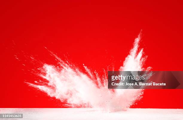 explosion by an impact of a cloud of particles of powder and smoke of color white on a red background. - destruction stock pictures, royalty-free photos & images