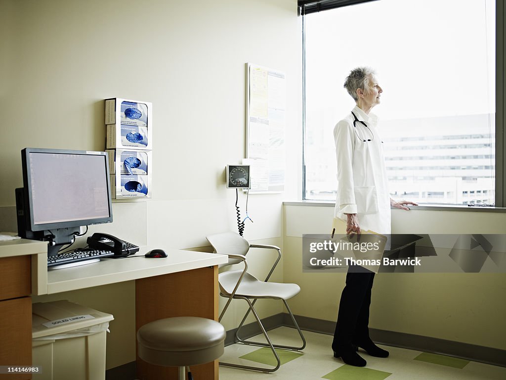 Doctor standing looking out window of exam room
