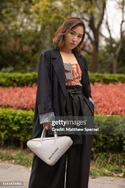 Guest is seen on the street attending Shanghai Fashion Week A/W 2019/2020 wearing black oversized blazer and pants, grey triangle Balenciaga bag on...