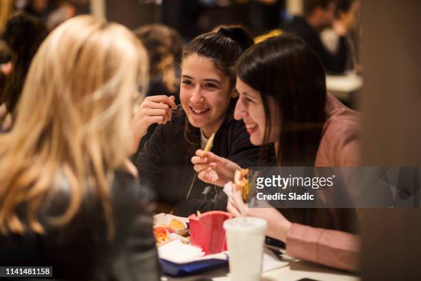 essen und spaß - girls laughing eating sandwich stock-fotos und bilder