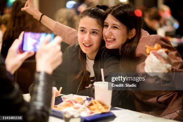 cibo e divertimento - girls laughing eating sandwich foto e immagini stock