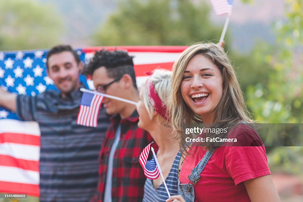Group of millennial friends hold a large American flag