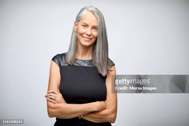 portrait of confident mature businesswoman smiling - arms crossed stock pictures, royalty-free photos & images