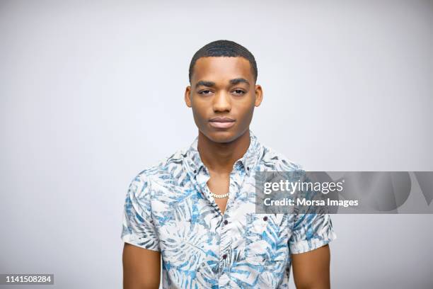 serious young man wearing foliate patterned shirt - manga curta - fotografias e filmes do acervo