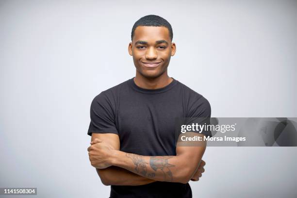 portrait of smiling tattooed man with arms crossed - portrait white background confidence stock-fotos und bilder