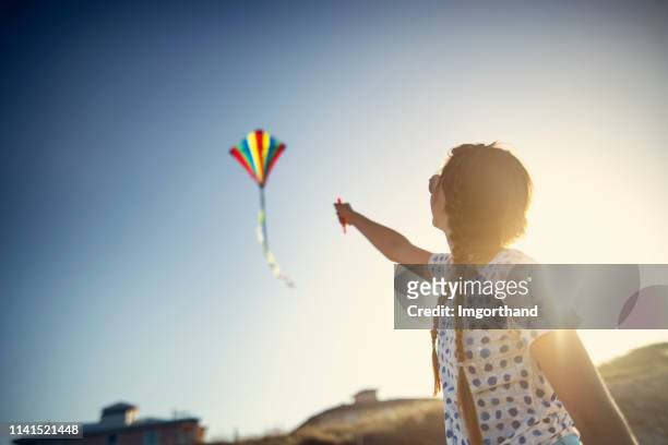 teenage girl flying a kite on a beach - kite flying stock pictures, royalty-free photos & images