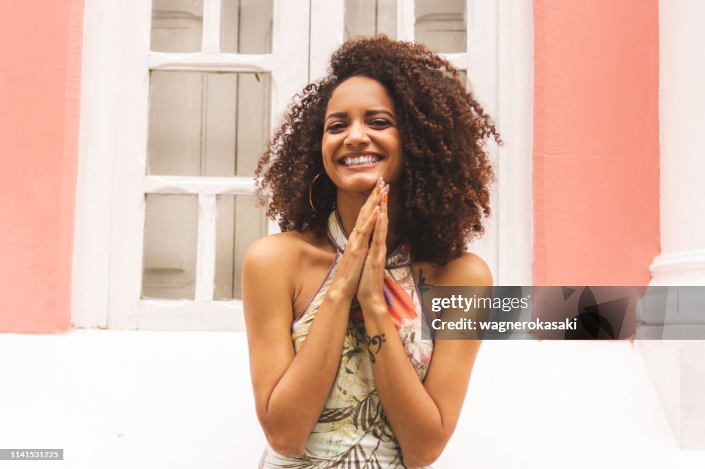 Portrait of a brazilian girl greeting you with hands together