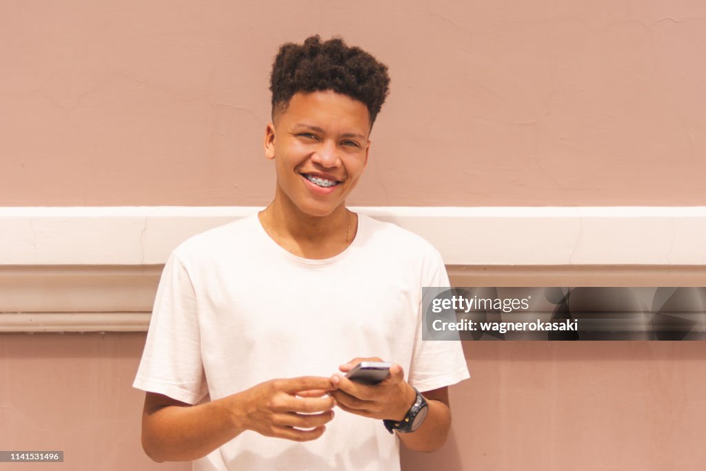 Portrait of a brazilian guy using smartphone looking at you