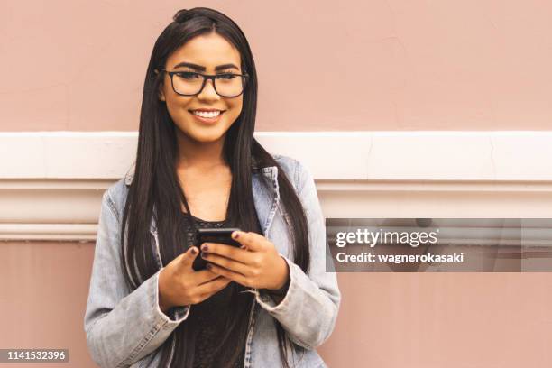 retrato de una chica brasileña usando un teléfono inteligente que te mira - testimonial fotografías e imágenes de stock