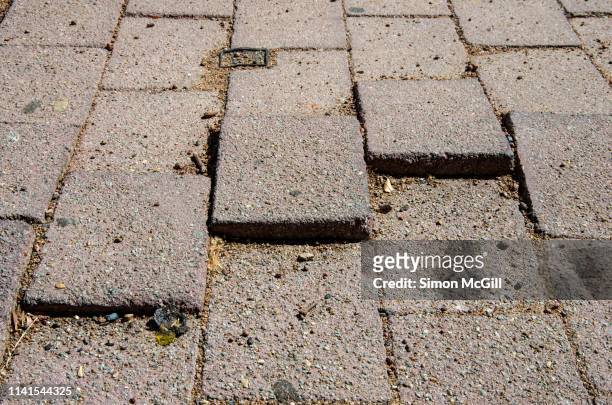uneven paving stones present a trip hazard on a pedestrian walkway - block paving stock-fotos und bilder