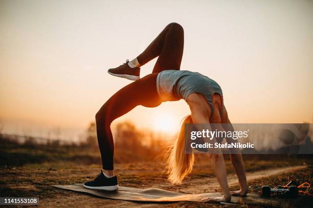 woman doing exercises in meadow - downward facing dog position stock pictures, royalty-free photos & images