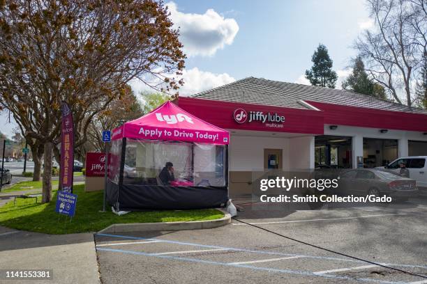 Tent and building with logos for automotive company Jiffy Lube and ridesharing company Lyft, during a partnership by the companies to recruit more...