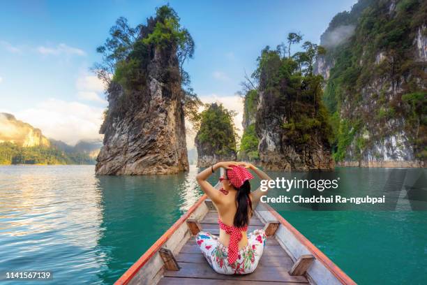 happy woman traveler on boat her arms open feeling freedom, ratchaprapa dam in khao sok national park, thailand, surat thani,travel in thailand, beautiful destination asia, summer holiday outdoors vacation trip - provincia-di-phuket foto e immagini stock