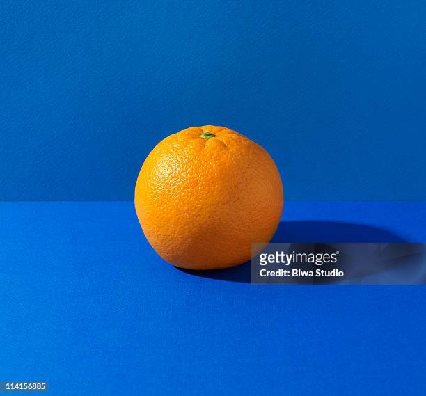 orange on blue background - obst stock-fotos und bilder