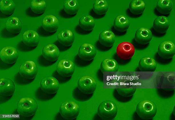 one red apple with many green apples - opvallen in een menigte stockfoto's en -beelden