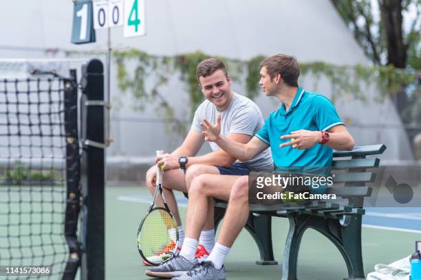 two males relax on a bench after playing a tennis match - country club stock pictures, royalty-free photos & images