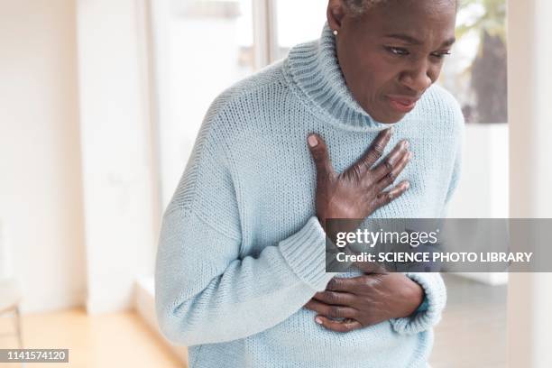 woman touching chest in pain - chest pain stock-fotos und bilder