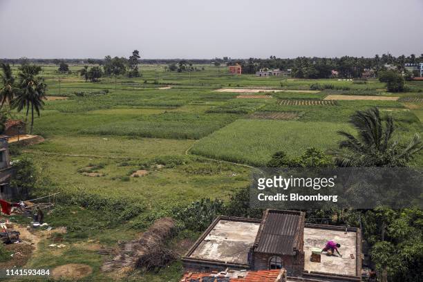 Woman labors on the roof of a building as fields stand at the site of the once-proposed Tata Motors Ltd. Factory in Singur, West Bengal, India, on...