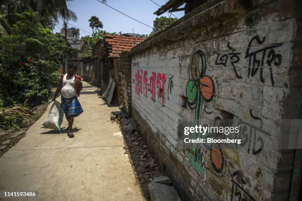 Man walks past the logo of the All India Trinamool Congress party painted on a wall on a building near the site of the once-proposed Tata Motors Ltd....