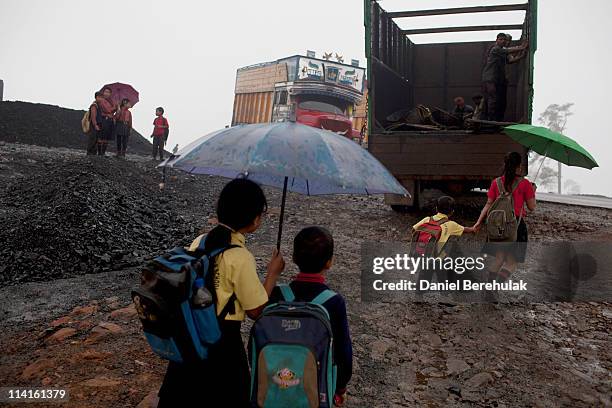 School children walk through a coal depot on their way home from school on April 14, 2011 near Lad Rymbai, in the district of Jaintia Hills, India....