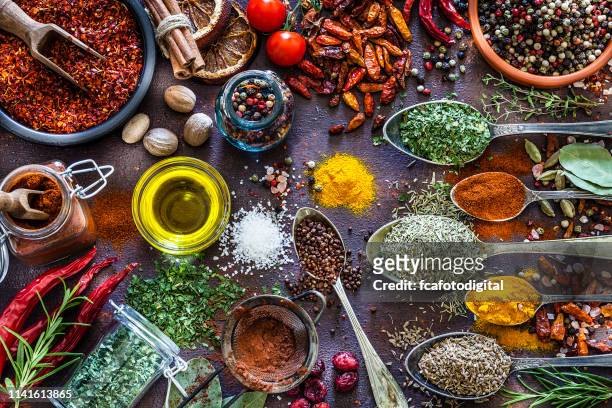 spices and herbs shot from above on rustic brown table - spice stock pictures, royalty-free photos & images
