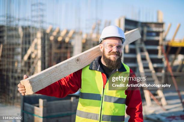 木製のボードと笑顔を運ぶ建設労働者の肖像。 - wood worker posing ストックフォトと画像