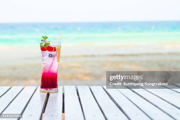 mix berry soda cocktail on the tropical beach with blue sky. contains a mixture of soda and berry-sweetened water decorated with strawberries, lemon, blackberries and cherries. - blackberry style lounge stock pictures, royalty-free photos & images