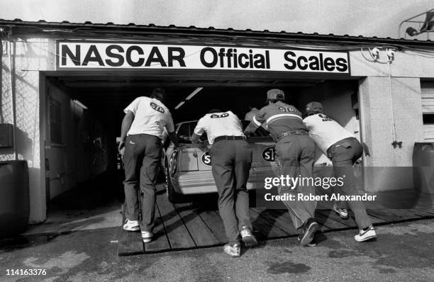 Members of the Richard Petty NASCAR crew push Petty's STP Pontiac into the inspection station at the Daytona International Speedway prior to the...