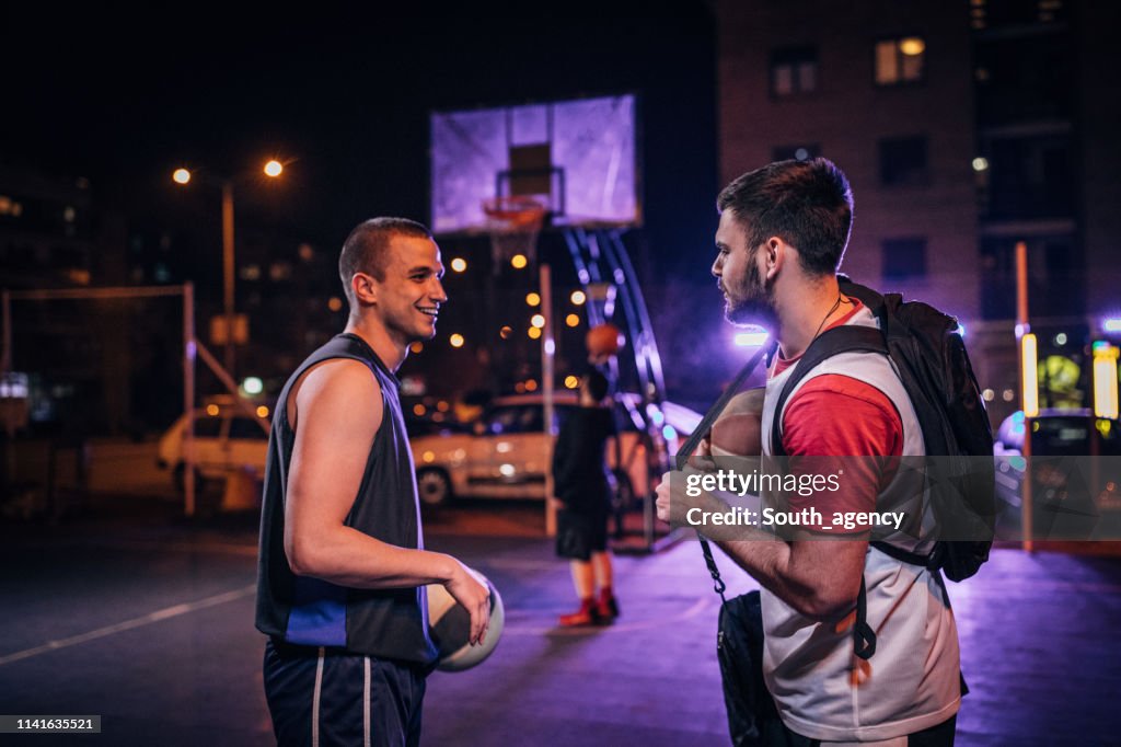 Amigos de streetball na corte ao ar livre na noite