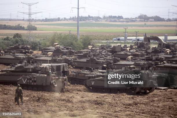 Israeli soldiers walks in front of a Merkava tanks, stationed near the border with the Gaza Strip on May 6, 2019 in Mavkim, Israel. Palestinian...