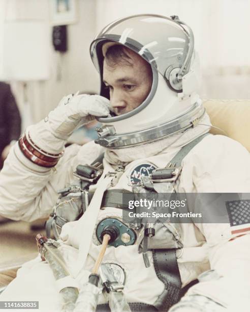 Pilot Michael Collins adjusts the helmet of his space suit in the Ready Room at Cape Kennedy in Florida, before NASA's Gemini 10 mission, July 1966.