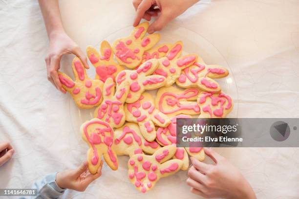 overhead view of family group taking home,ade easter biscuits off a plate on a dining table - family rabbit stock pictures, royalty-free photos & images