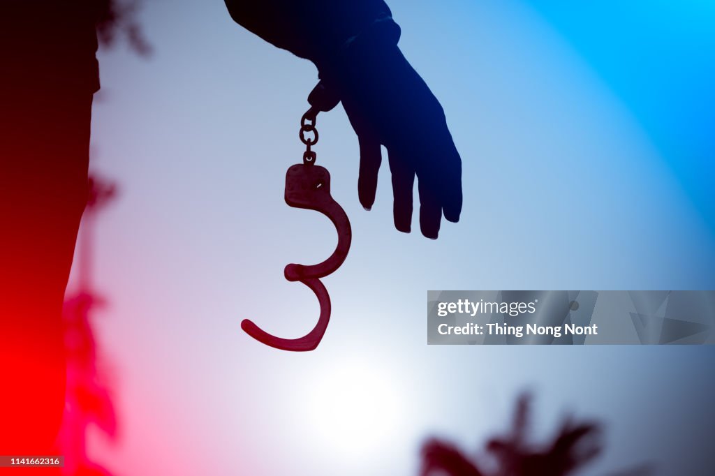 A prisoner behind bars with hands cuffed