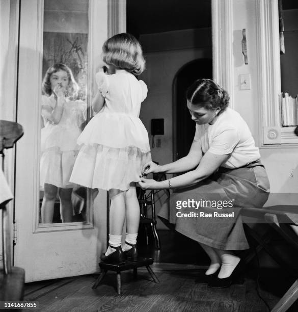 Little girl gets her 'dream' dress handmade and tailored by a dressmaker at a McCall Pattern Company shop, US, circa 1950.