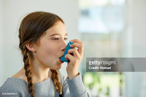 close-up van meisje met behulp van astma inhalator thuis - asthma stockfoto's en -beelden