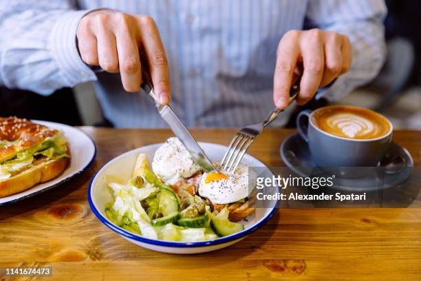 man eating breakfast with poached eggs, fresh salad and coffee - eggs benedict stock pictures, royalty-free photos & images