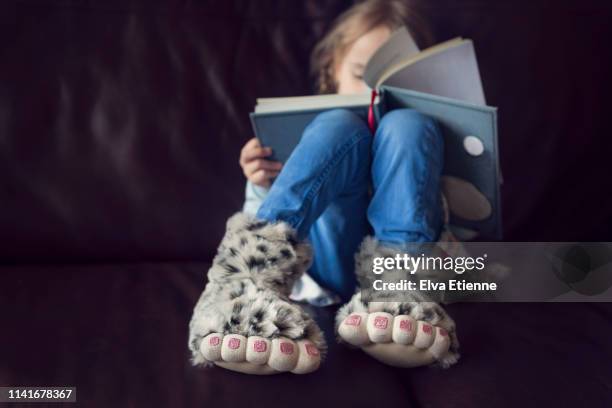 child wearing novelty monster feet slippers, reading a book - toe stock pictures, royalty-free photos & images