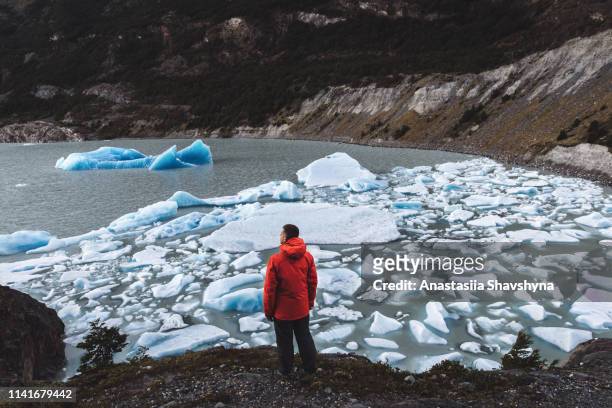 man enjoying the view of icebergs, glacier and mountains at torres del paine - glacier stock pictures, royalty-free photos & images
