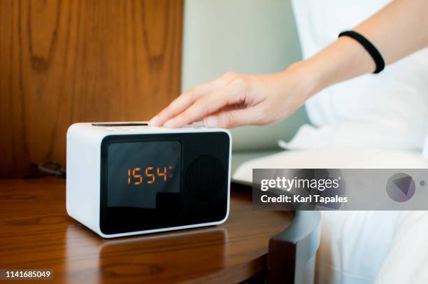 a young woman is turning off the snooze button of a digital alarm clock - alarm clock hand stock pictures, royalty-free photos & images