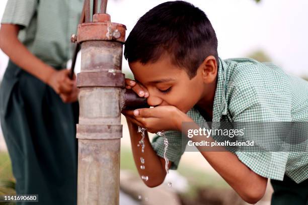 thirsty child drinking water on water pump - boy drinking water stock pictures, royalty-free photos & images