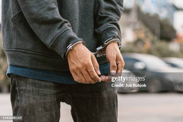 save to boardlooking down at handcuffed male hands on black background - häftling stock-fotos und bilder